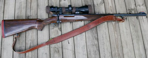Waldkauz Gewehrriemen Rufus, Gewehrriemen ist montiert an einer Waffe welche auf einem Holzboden liegt